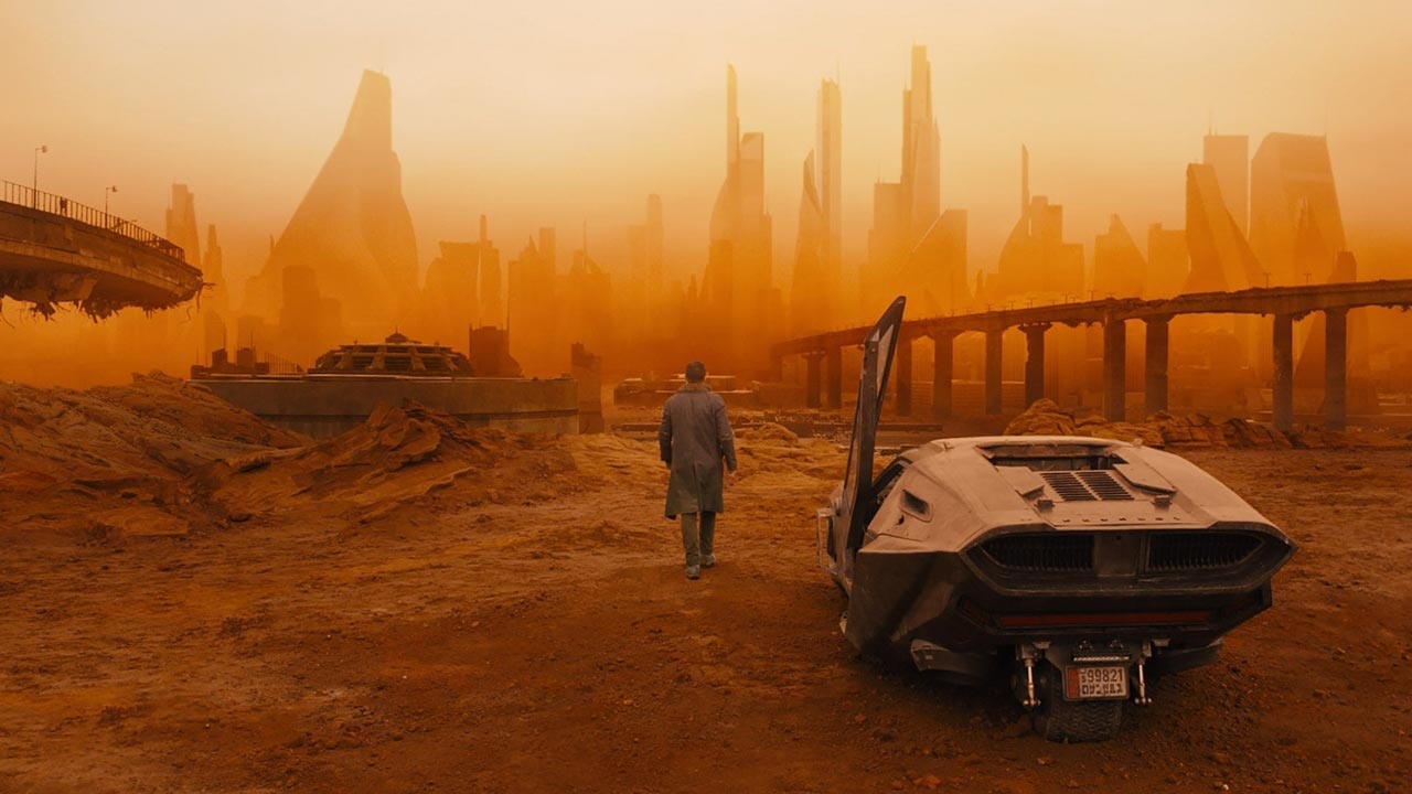 Blade Runner "K" walks toward a desolate cityscape.