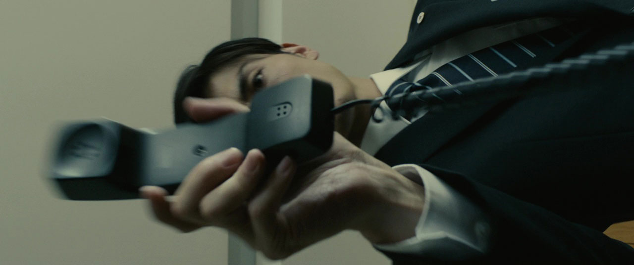 A man in a suit puts down a phone receiver.